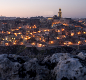 Historische Stadtansicht bei Dämmerung mit funkelnden Lichtern und markantem Turm.
